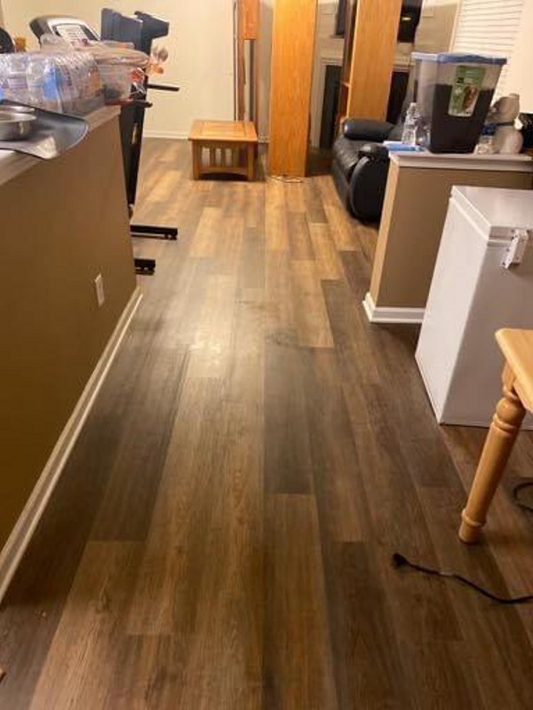 Open-plan kitchen and dining area with wood laminate flooring, highlighting practical design for flooring services by a home improvement expert.