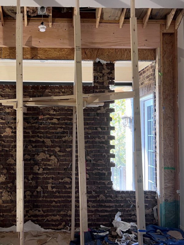 Construction site in progress showing exposed wooden beams and brickwork, illustrating the detailed process of home transformation services performed by a general contractor.